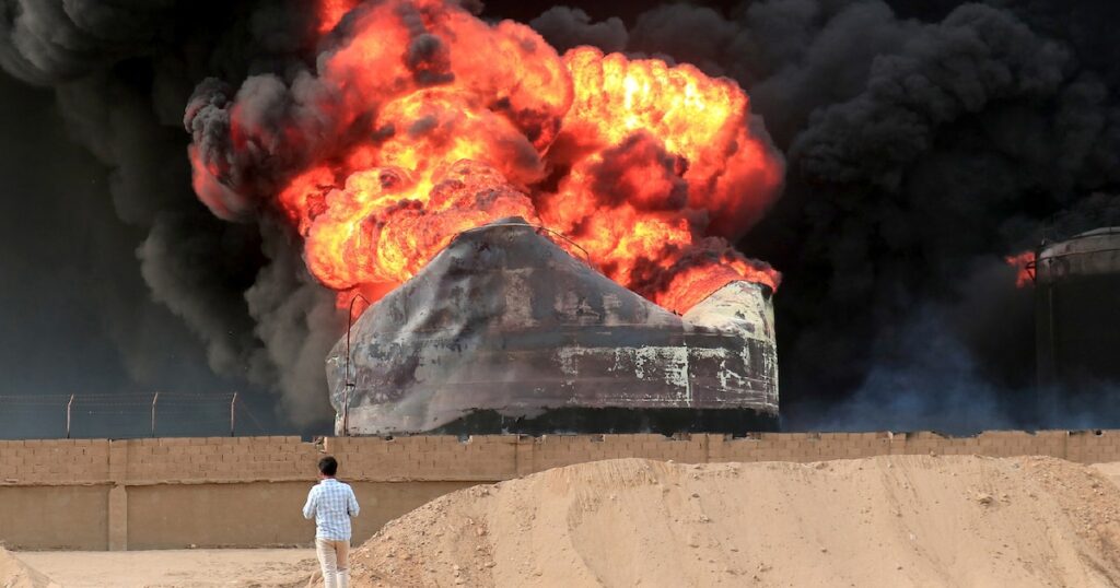 Un homme devant un incendie qui fait rage dans des réservoirs de stockage de pétrole, bombardés par Israël au port de Hodeida tenu par les rebelles Houthis au Yémen, le 21 juillet 2024