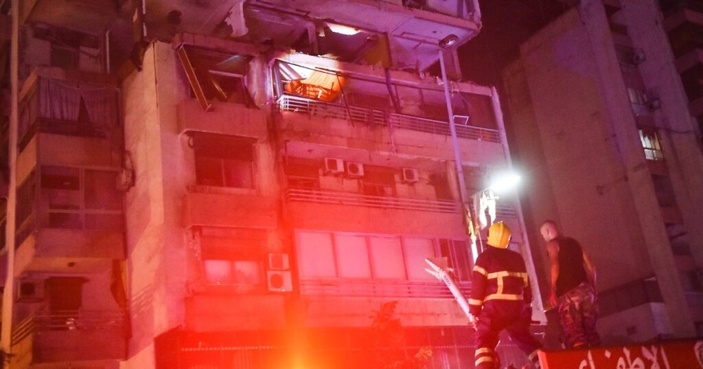 Des pompiers devant un immeuble touché par une frappe aérienne israélienne dans le quartier de Cola à Beyrouth, le 30 septembre 2024