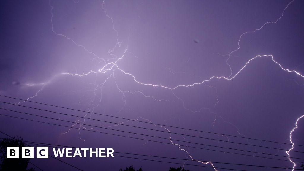 Night sky turning a purple hue as fork lighting spreads across the sky.