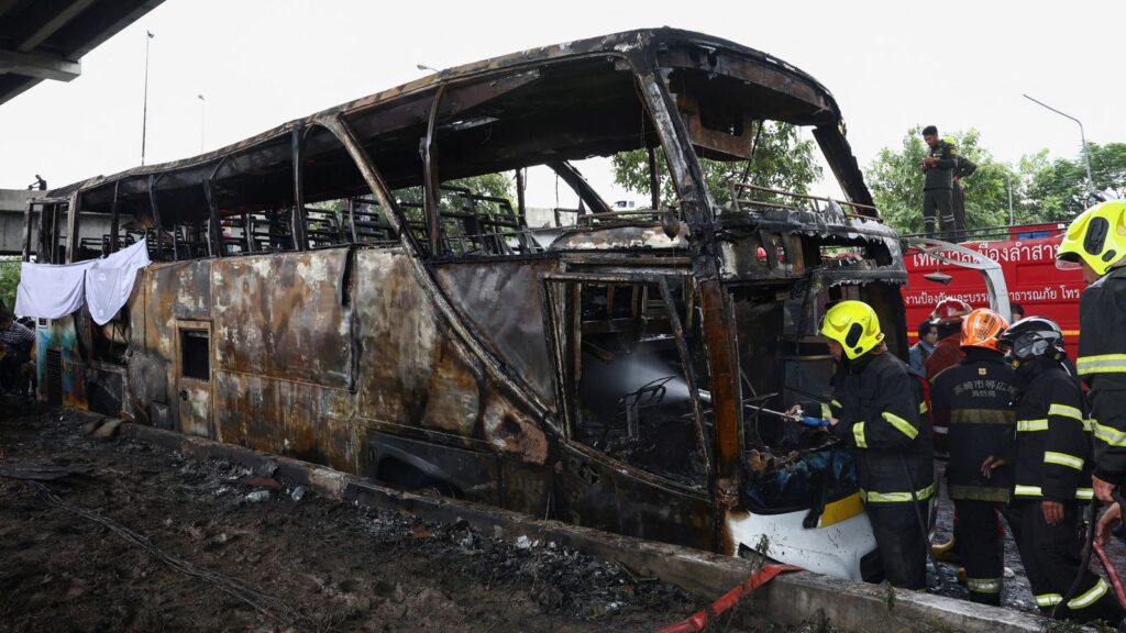 Firefighters work to extinguish a burning bus that was carrying teachers and students from Wat Khao Phraya school