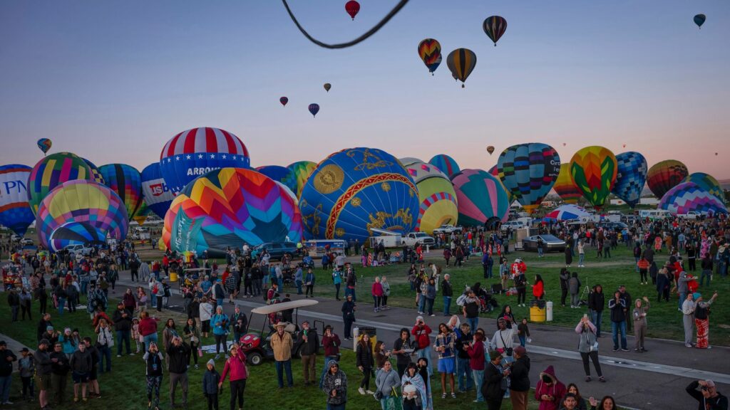 People watch as Meow Wolf's Skyworm hot air balloon takes flight during the Albuquerque International Balloon Fiesta at Balloon Fiesta Park in Albuquerque, N.M., on Tuesday, Oct. 8, 2024. (Chancey Bush/The Albuquerque Journal via AP)