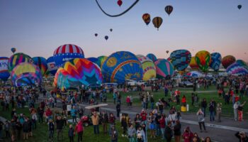 People watch as Meow Wolf's Skyworm hot air balloon takes flight during the Albuquerque International Balloon Fiesta at Balloon Fiesta Park in Albuquerque, N.M., on Tuesday, Oct. 8, 2024. (Chancey Bush/The Albuquerque Journal via AP)