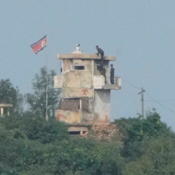 FILE - North Korean soldiers work at the North's military guard post as a North Korean flag flutters in the wind, are seen from Paju, South Korea, near the border with North Korea, Thursday, Oct. 10, 2024. (AP Photo/Ahn Young-joon, File)