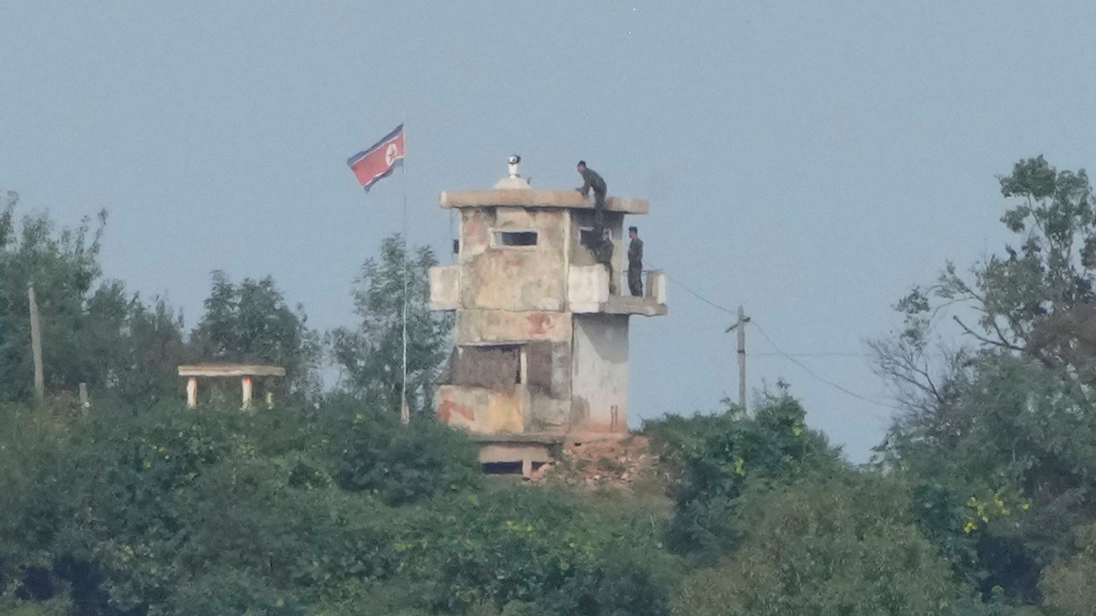 FILE - North Korean soldiers work at the North's military guard post as a North Korean flag flutters in the wind, are seen from Paju, South Korea, near the border with North Korea, Thursday, Oct. 10, 2024. (AP Photo/Ahn Young-joon, File)