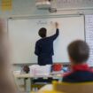 A teacher wearing a protective face mask works with pupils after they have returned to their classroom at the Trinite public school in the Groix island, on May 12, 2020, two days after France eased lockdown measures to curb the spread of the COVID-19 pandemic, caused by the novel coronavirus. (Photo by Loic VENANCE / AFP)