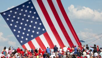 Le drapeau américain flotte au dessus de sympathisants venus assister au meeting où Donald Trump a été la cible de tirs à Butler (nord-est des Etats-Unis), le 13 juillet 2024