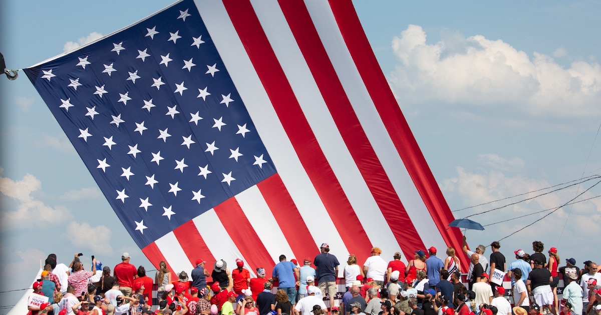 Le drapeau américain flotte au dessus de sympathisants venus assister au meeting où Donald Trump a été la cible de tirs à Butler (nord-est des Etats-Unis), le 13 juillet 2024