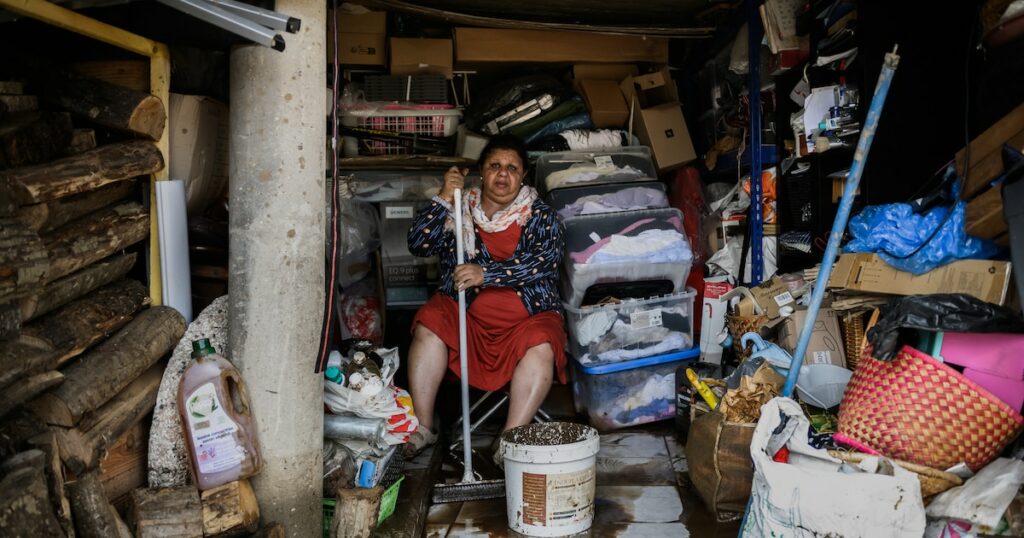 Une femme essuie la boue du sol d'une maison le 18 octobre 2025 dans le village de Limony, dans le sud de la France, un jour après que le village ait été coincé dans des inondations suite à de fortes pluies dans le département de l'Ardèche.