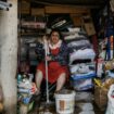 Une femme essuie la boue du sol d'une maison le 18 octobre 2025 dans le village de Limony, dans le sud de la France, un jour après que le village ait été coincé dans des inondations suite à de fortes pluies dans le département de l'Ardèche.