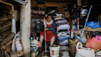 Une femme essuie la boue du sol d'une maison le 18 octobre 2025 dans le village de Limony, dans le sud de la France, un jour après que le village ait été coincé dans des inondations suite à de fortes pluies dans le département de l'Ardèche.