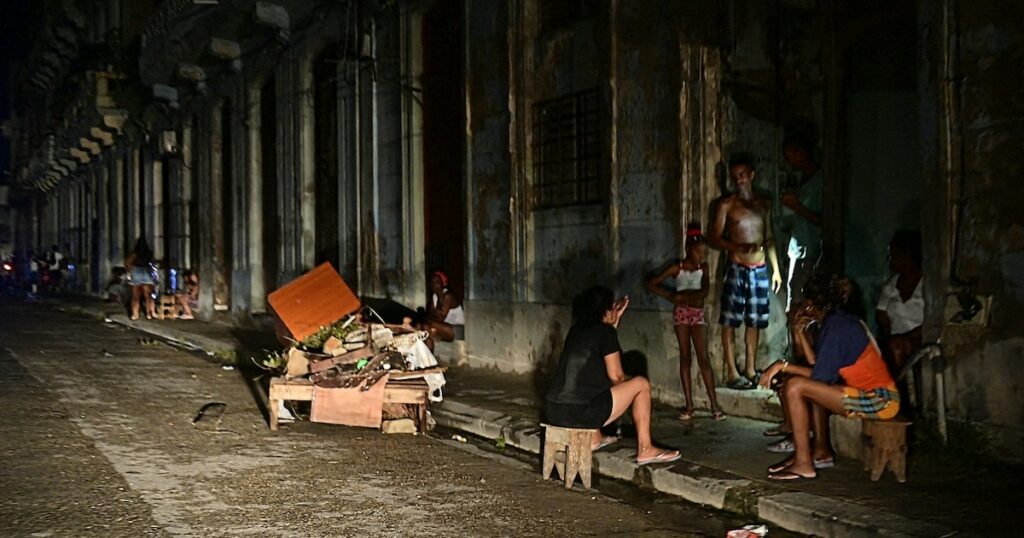 Des Cubains discutent la nuit dans une rue lors d'une panne nationale causée par une défaillance du réseau électrique à La Havane, le 18 octobre 2024.