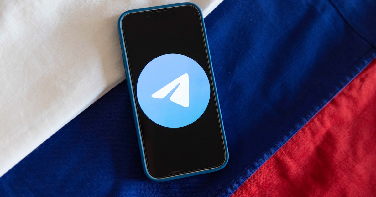 Illustration montrant le logo de l'application de messagerie Telegram affiché sur un téléphone portable avec les couleurs du drapeau russe