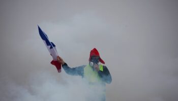 Un "gilet jaune" tient le drapeau français dans la fumée des gaz lacrymogènes lors d'une manifestation contre la hausse du coût de la vie, le 1er décembre 2018 à Paris