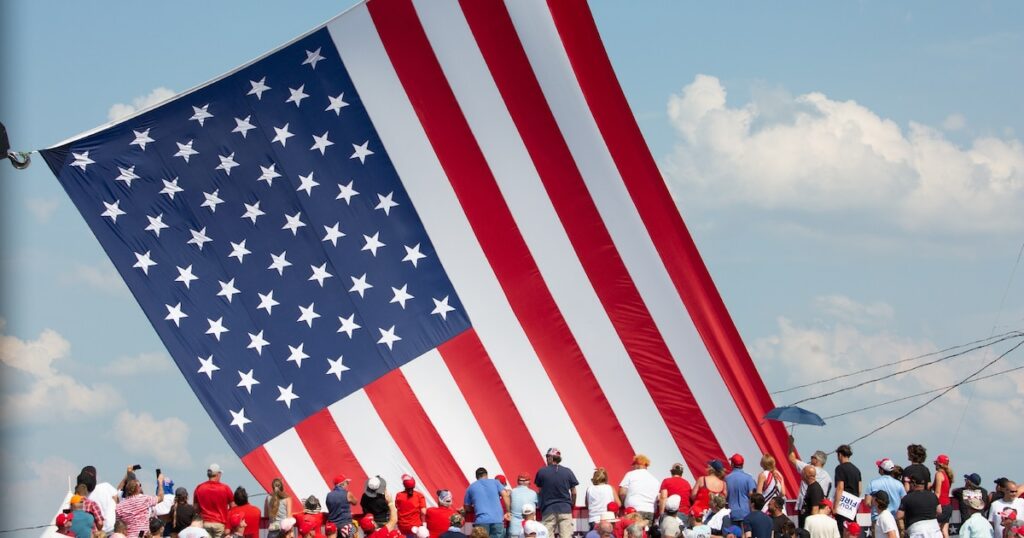 Le drapeau américain flotte au dessus de sympathisants venus assister au meeting où Donald Trump a été la cible de tirs à Butler (nord-est des Etats-Unis), le 13 juillet 2024