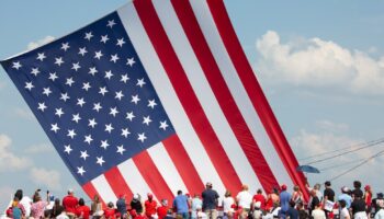 Le drapeau américain flotte au dessus de sympathisants venus assister au meeting où Donald Trump a été la cible de tirs à Butler (nord-est des Etats-Unis), le 13 juillet 2024