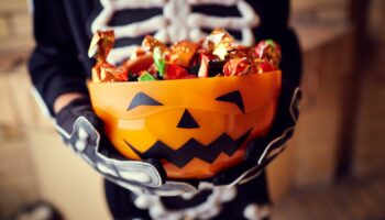 Boy in skeleton costume holding bowl full of candies