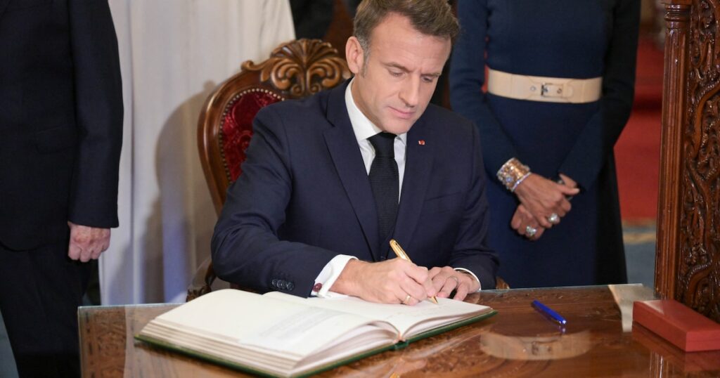 Le président français Emmanuel Macron, accompagné de son épouse Brigitte, signe le livre d'or à la fin d'une visite au mausolée de Mohamed V à Rabat, le 29 octobre 2024.