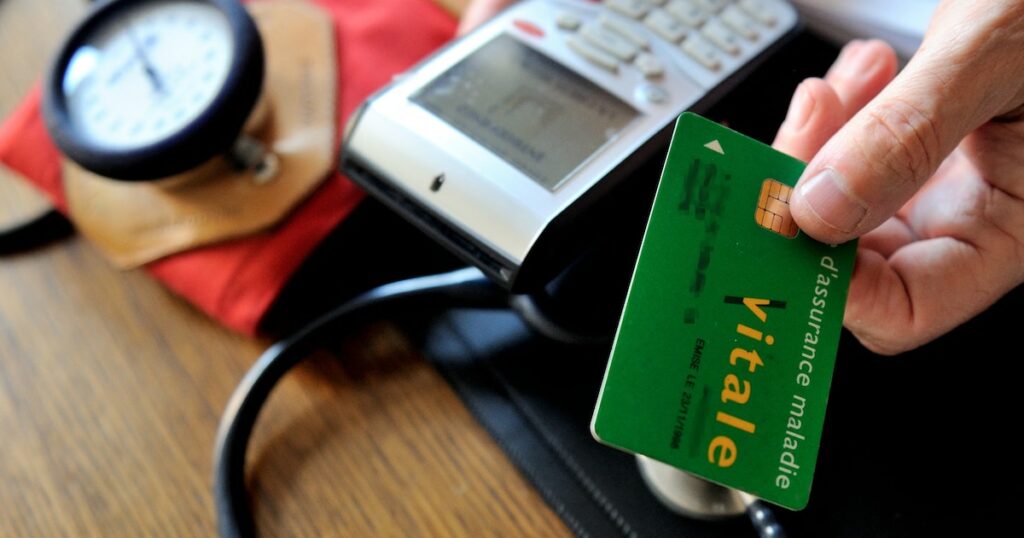 A doctor gives back a French health insurance electronic card (carte vitale) after using it in a connected reader on September 23, 2013 in Godewaersvelde, northern France, during medical exams.  AFP PHOTO / PHILIPPE HUGUEN (Photo by PHILIPPE HUGUEN / AFP)