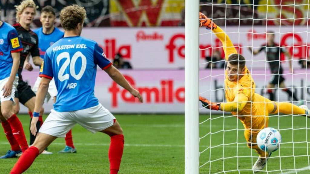 Union Berlins Tom Rothe (2. v l) trifft zum 0:2 gegen Kiels Torwart Timon Weiner (r). Foto: Axel Heimken/dpa