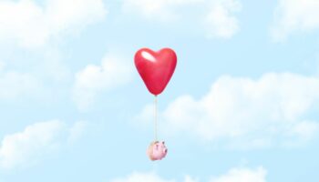 Symbolbild Finanzen in der Beziehung: Ein Sparschwein schwebt im Himmel, es ist an einen Herz-Luftballon gebunden