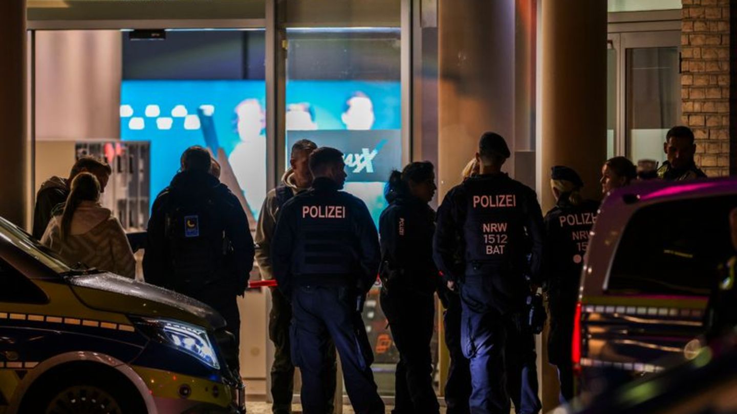 Polizeibeamte und Rettungsdienst stehen vor dem Kino in der Krefelder Innenstadt. Foto: Christoph Reichwein/dpa