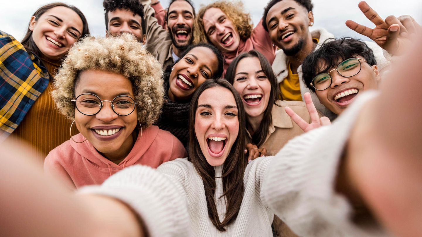 Eine Frau lacht mit vielen Freundin auf einem Selfie.