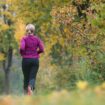 Wetter heute: Eine Frau läuft in Baden-Württemberg an herbstlich verfärbten Laubbäumen vorbei