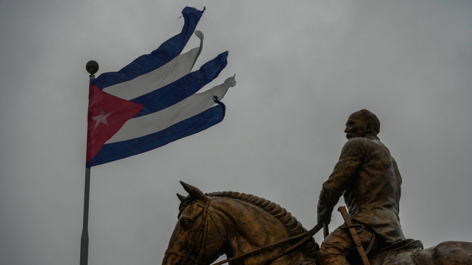 A Cuban flag shredded by the winds of Hurricane Rafael flies above the statue of General Calixto Garcia in Havana, Cuba Pic: AP