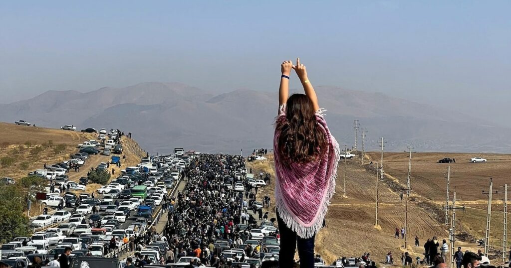 Image UGC publiée sur Twitter, le 26 octobre 2022, d'une femme non voilée debout sur le toit d'une voiture, des milliers de personnes se dirigeant vers un cimetière à Saghez, dans l'ouest de l'Iran, pour marquer le 40e jour du décès de Mahsa Amini