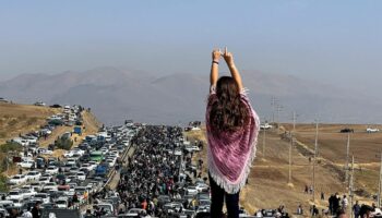 Image UGC publiée sur Twitter, le 26 octobre 2022, d'une femme non voilée debout sur le toit d'une voiture, des milliers de personnes se dirigeant vers un cimetière à Saghez, dans l'ouest de l'Iran, pour marquer le 40e jour du décès de Mahsa Amini