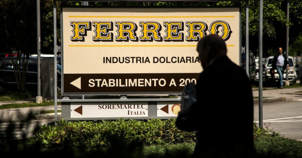 Cette photo prix le 29 mai 2019 à Alba montre un homme marchant près du logo du fabricant italien de chocolat de marque Ferrero.