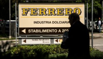 Cette photo prix le 29 mai 2019 à Alba montre un homme marchant près du logo du fabricant italien de chocolat de marque Ferrero.