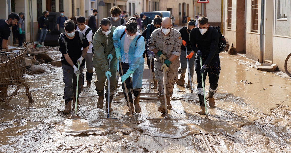 Des personnes et des soldats participent à une opération de nettoyage dans une rue inondée à Catarroja, dans la région de Valence, dans l'est de l'Espagne, à la suite d'inondations meurtrières, le 6 novembre 2024