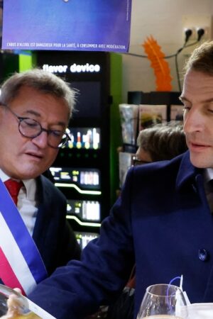 Le président français Emmanuel Macron (à droite) et le maire de Vierzon, Nicolas Sansu (à gauche), boivent un verre de vin dans un café de la ville de Vierzon, le 7 décembre 2021. (Photo de Ludovic MARIN / AFP)