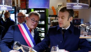 Le président français Emmanuel Macron (à droite) et le maire de Vierzon, Nicolas Sansu (à gauche), boivent un verre de vin dans un café de la ville de Vierzon, le 7 décembre 2021. (Photo de Ludovic MARIN / AFP)