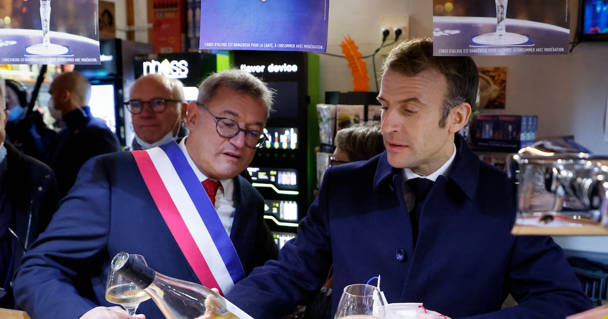 Le président français Emmanuel Macron (à droite) et le maire de Vierzon, Nicolas Sansu (à gauche), boivent un verre de vin dans un café de la ville de Vierzon, le 7 décembre 2021. (Photo de Ludovic MARIN / AFP)