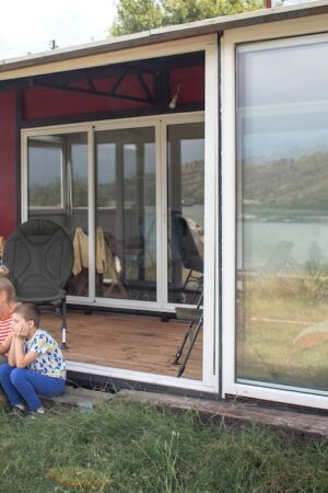 Une mère avec deux enfants et un chien profitant de leur maison-container.