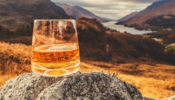 Glass of single malt Scotch Whisky on an old rock above Glenfinnan in the West Highlands of Scotland.