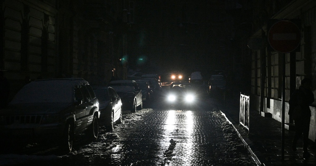 Des voitures empruntent une rue de Lviv (Ukraine) plongée dans le noir en raison de coupures d'électricité le 24 novembre 2022