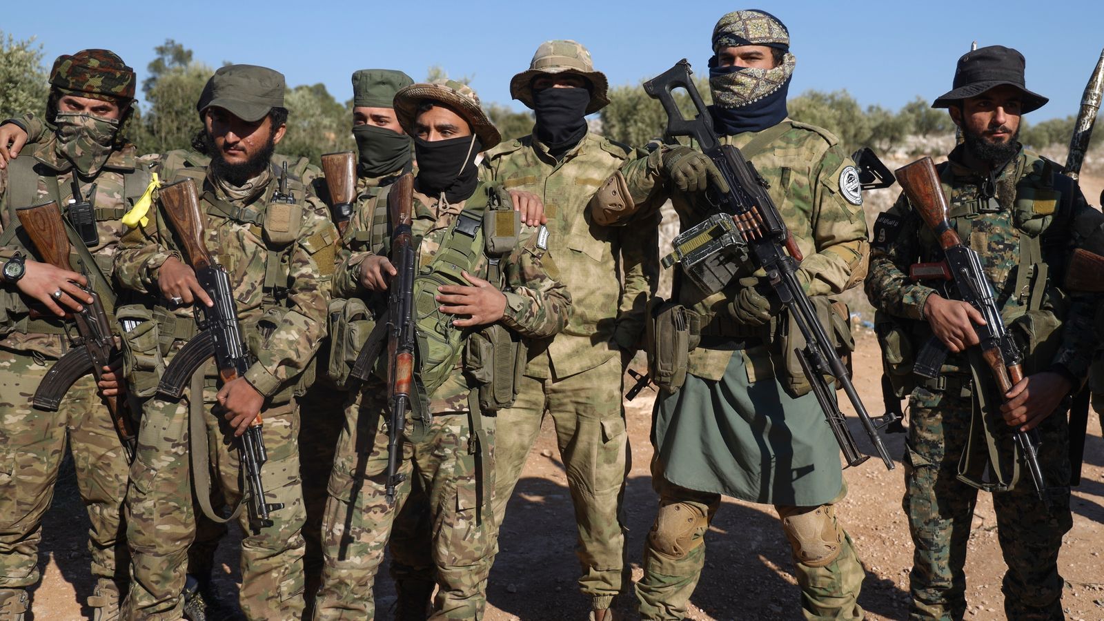 Syrian opposition fighters stand in formation after entering the village of Anjara, western outskirts of Aleppo, Syria, Thursday Nov. 28, 2024, part of  their major offensive on government-controlled areas in the country's northwestern Syria. (AP Photo/Omar Albam)