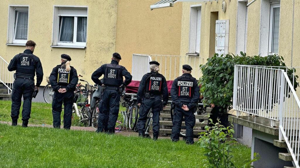 Fünf Polizistinnen und Polizisten stehen vor einem Haus