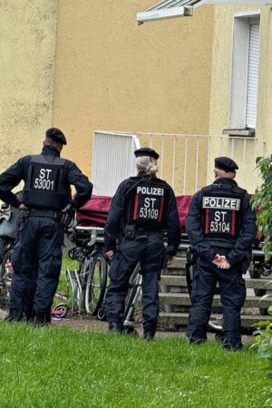 Fünf Polizistinnen und Polizisten stehen vor einem Haus