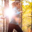 Jogging-Outfit im Herbst: Junge Frau joggt durch herbstlichen Wald