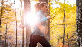 Jogging-Outfit im Herbst: Junge Frau joggt durch herbstlichen Wald