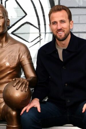 Harry Kane sat next to his statue at Peter May Sports Centre in London.