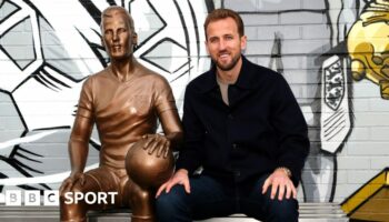 Harry Kane sat next to his statue at Peter May Sports Centre in London.