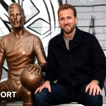 Harry Kane sat next to his statue at Peter May Sports Centre in London.