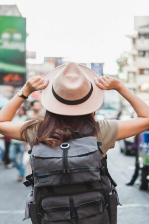 Eine Frau mit Sonnenhut läuft durch eine belebte Straße in Bangkok.