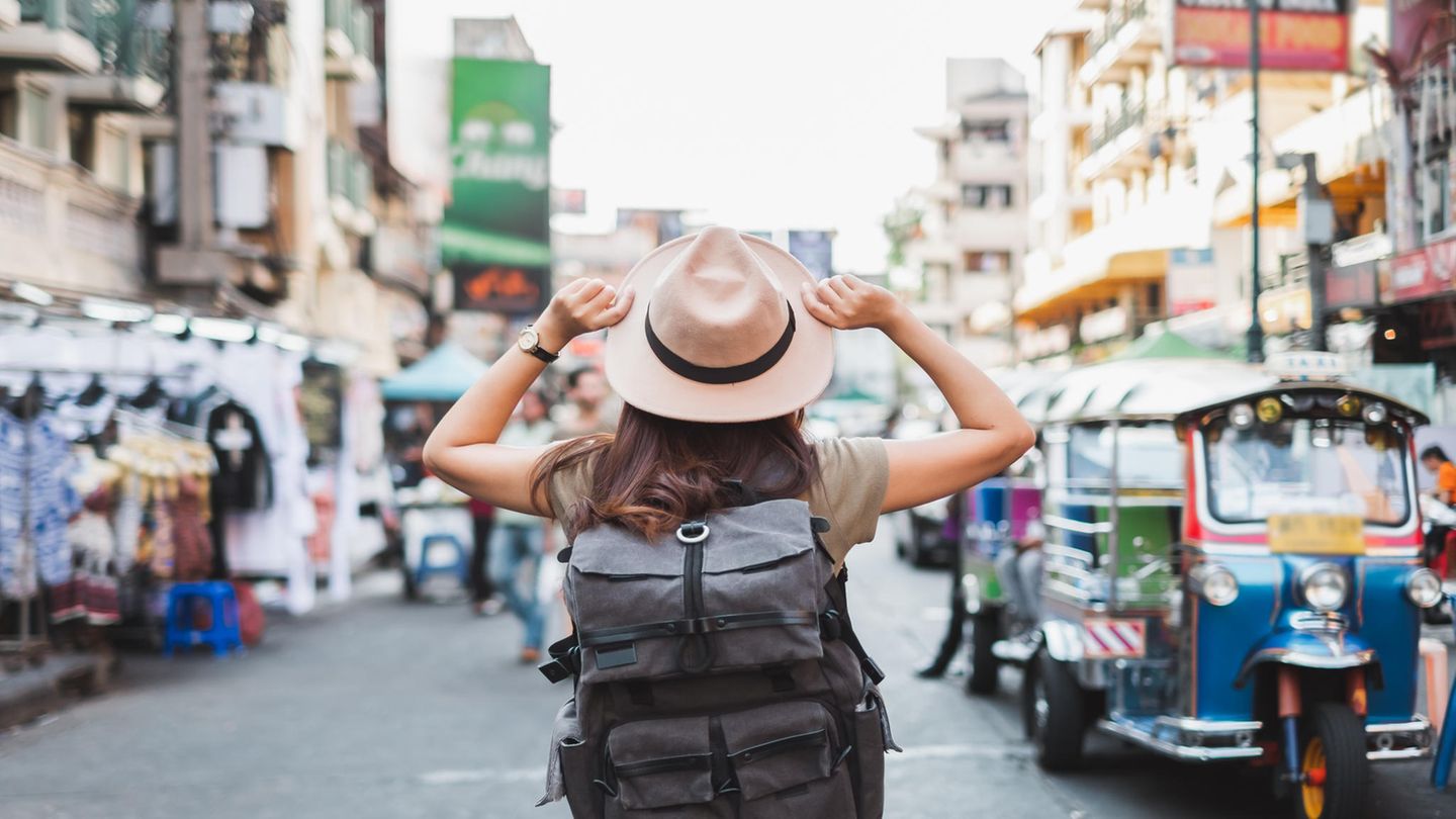 Eine Frau mit Sonnenhut läuft durch eine belebte Straße in Bangkok.