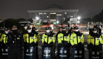 La police monte la garde devant la porte principale de l'Assemblée nationale à Séoul le 3 décembre 2024, après que le président sud-coréen Yoon Suk Yeol a déclaré la loi martiale d'urgence.